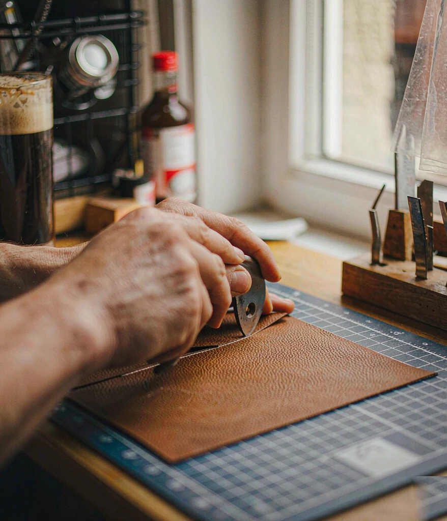 Hands cutting leather with a round knife