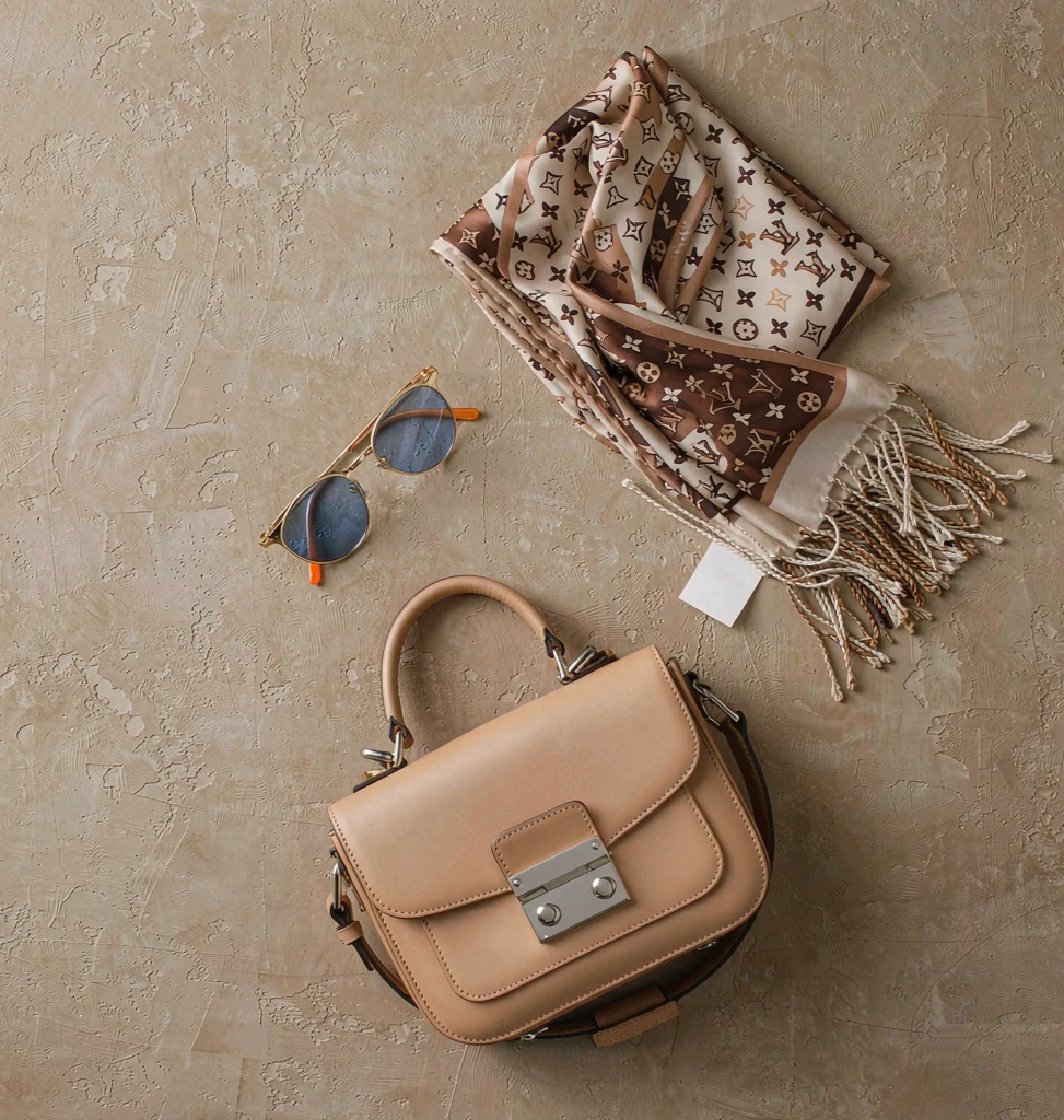 Tan leather handbag flat lay with sunglasses and a silk scarf